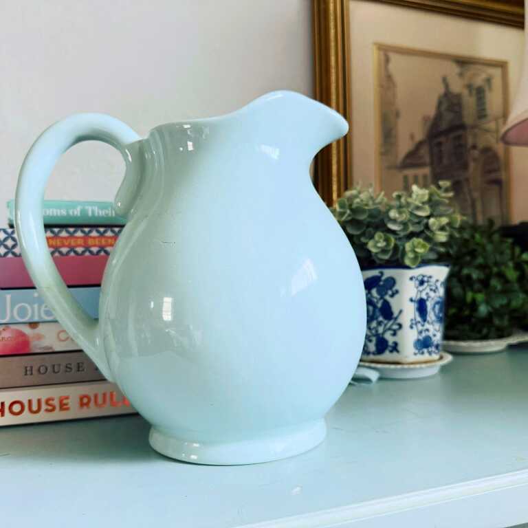 robin's egg blue pitcher on a table either books, art, and a plant